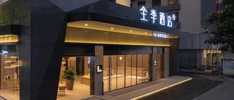 Exterior de un hotel con diseño moderno, que presenta una entrada destacada y una fachada bien iluminada.