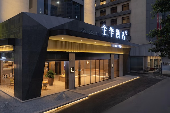A hotel exterior with a modern design, featuring a prominent entrance and a well-lit facade.