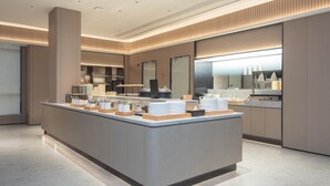 A modern hotel lobby with a central reception desk, a large mirror, and a kitchen area in the background. - Ji Hotel Guangzhou Baiyun Station Sanyuanli Avenue (Guangzhou)