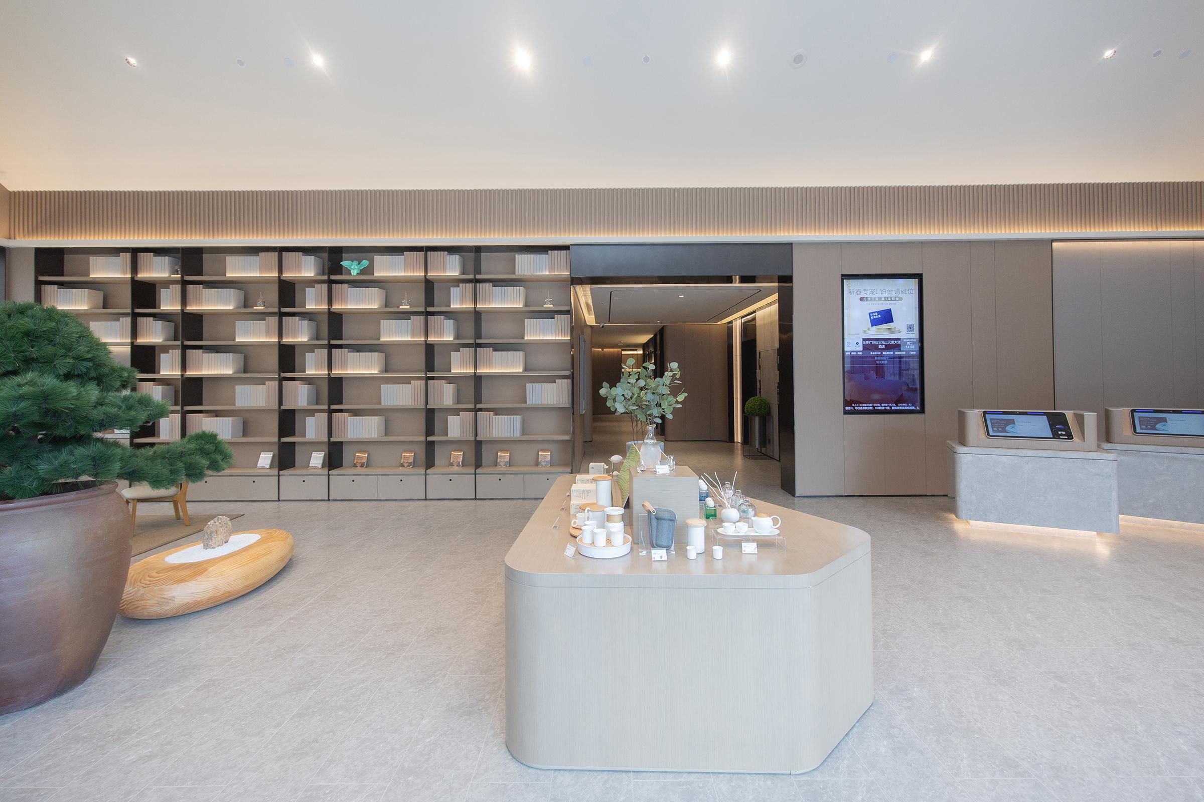 A modern interior with a reception desk, a large bookshelf, and a potted plant.