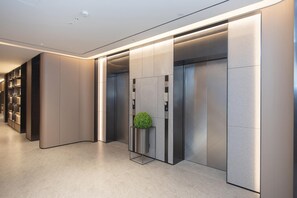 A modern elevator with a green spherical object on the control panel, surrounded by metallic walls and a lighted ceiling. - Ji Hotel Guangzhou Baiyun Station Sanyuanli Avenue (Guangzhou)