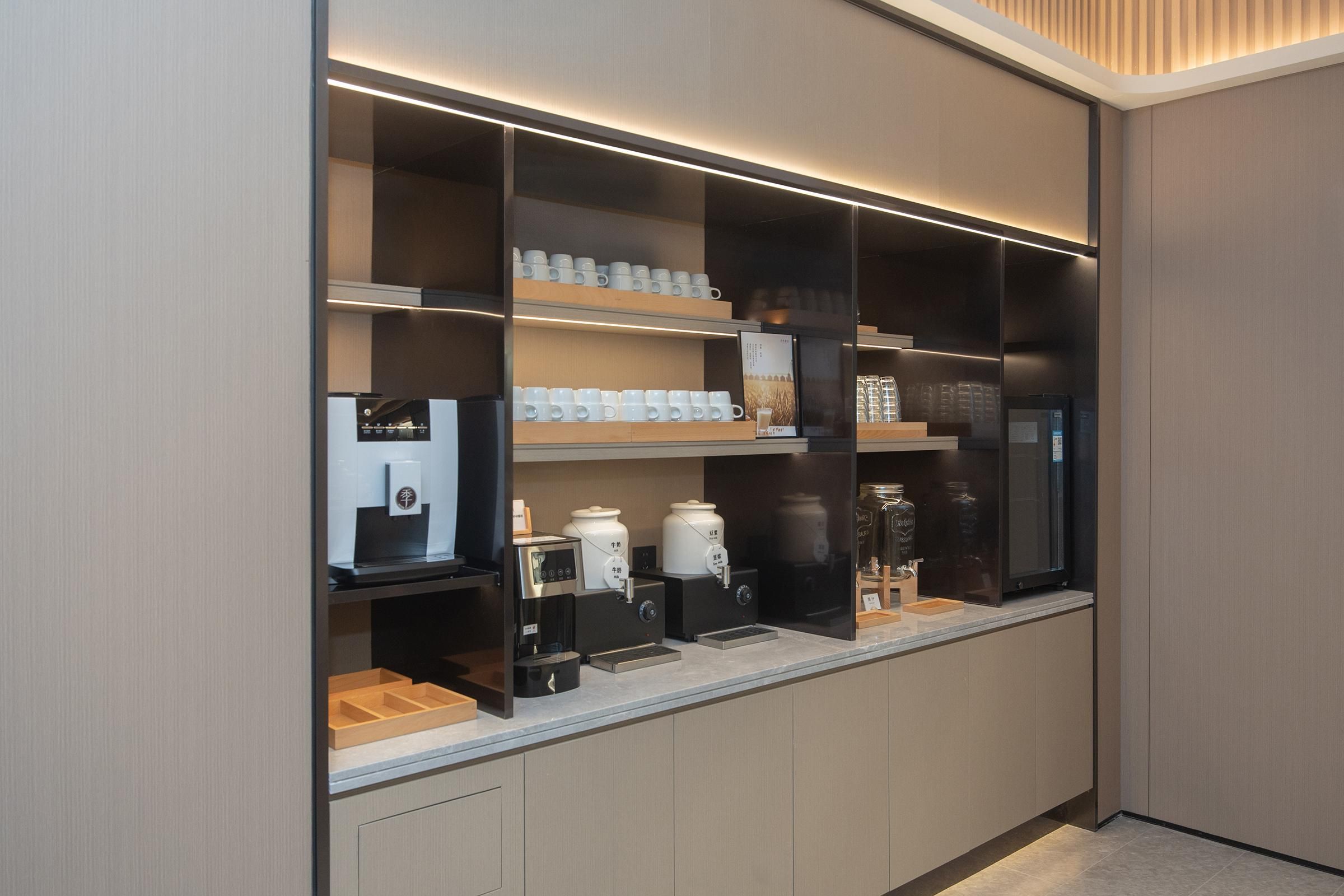A modern kitchen with built-in appliances, including a coffee machine, and shelves with cups and jars.