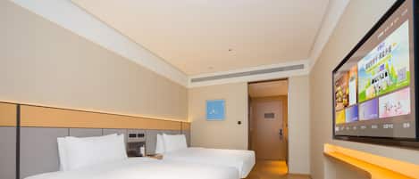 Ein Hotelzimmer mit zwei Betten, einem an der Wand befestigten Fernseher und einer Holzbank.