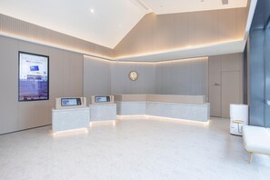 A modern reception area with a curved reception desk, a digital display, and a logo on the wall. - Ji Hotel Guangzhou Baiyun Station Sanyuanli Avenue (Guangzhou)
