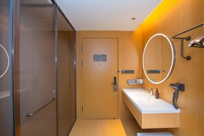 Une salle de bain moderne avec un meuble-lavabo en bois, un miroir avec éclairage intégré et une cabine de douche en verre.