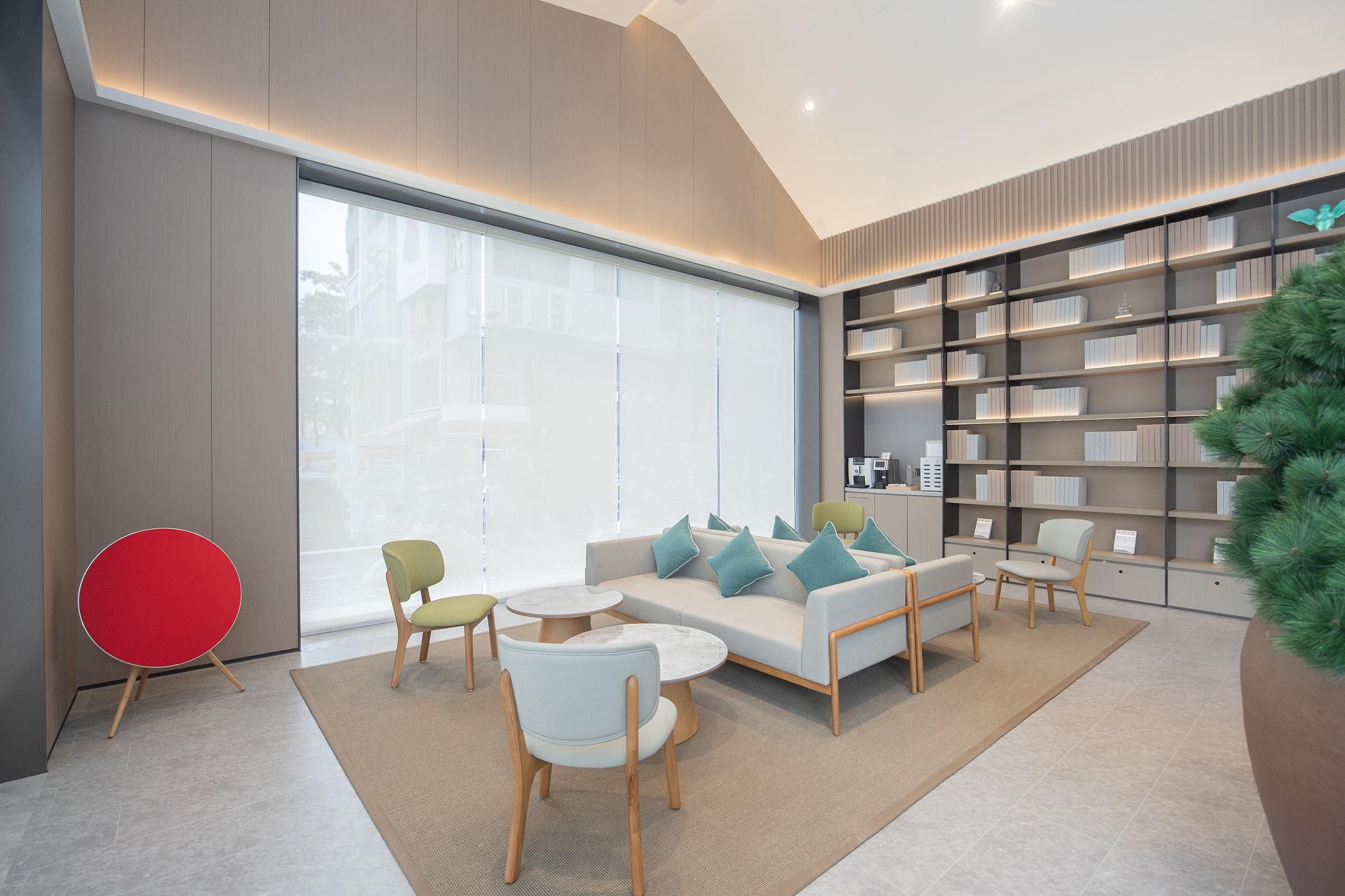 Uma sala de estar moderna com sofá, cadeiras, uma poltrona vermelha, estante e uma janela grande.