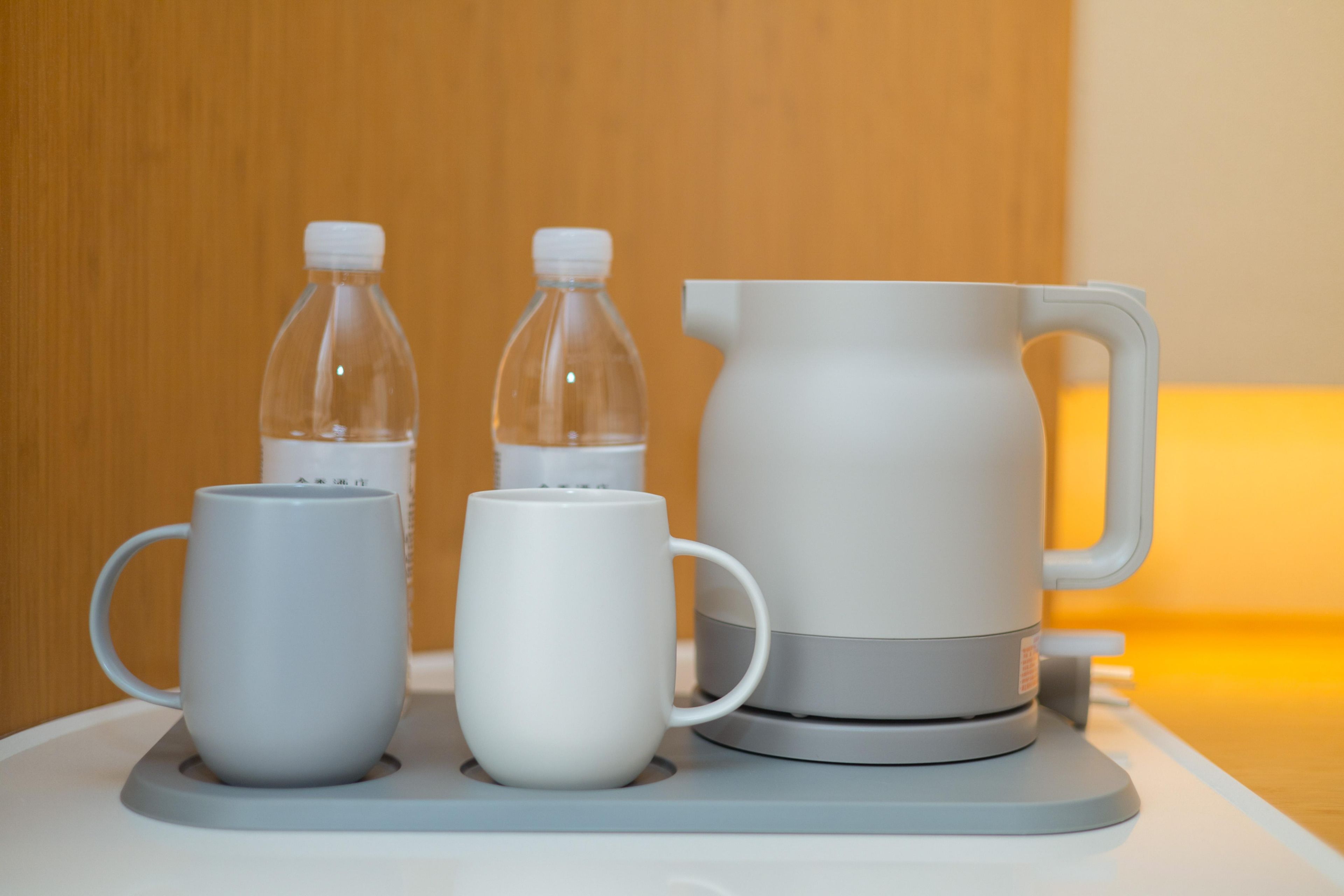 A table with two white mugs and two clear bottles, and a grey pitcher.
