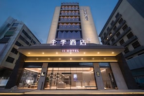 Exterior del Ji Hotel con fachada moderna, amplios ventanales y una entrada destacada.