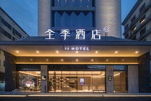 Entrada de hotel de diseño moderno, con un letrero destacado y un área de recepción con asientos.