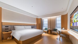 A modern hotel room with a large bed, a desk with a chair, a small table, and a TV mounted on the wall. - Ji Hotel Guangzhou Baiyun Station Sanyuanli Avenue (Guangzhou)