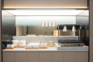 Una cocina moderna con estufa integrada, un lavamanos y una encimera con utensilios y platos.