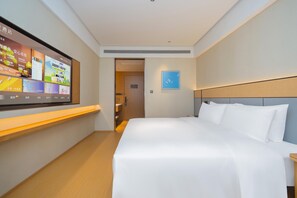 Habitación de hotel con una cama grande, un televisor de pantalla plana en la pared y una mesita.