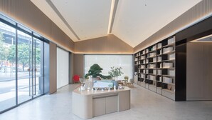 A modern interior with a reception desk, large windows, and a bookshelf. - Ji Hotel Guangzhou Baiyun Station Sanyuanli Avenue (Guangzhou)