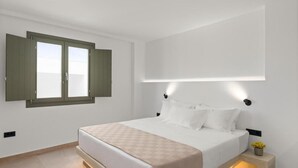 Quarto moderno com uma cama grande, uma janela com as persianas abertas e um candeeiro fixado na parede.