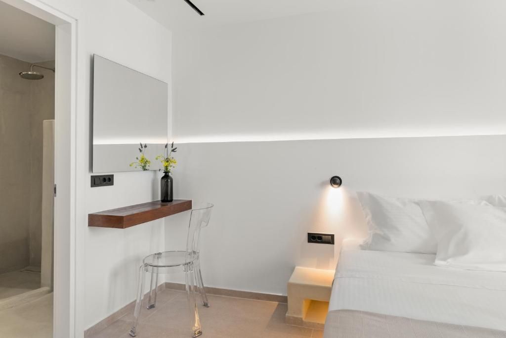 Een moderne slaapkamer met een bed, nachtkastje, spiegel en transparante stoel.