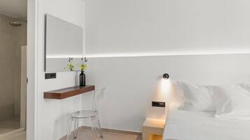 Een moderne slaapkamer met een bed, nachtkastje, spiegel en transparante stoel.