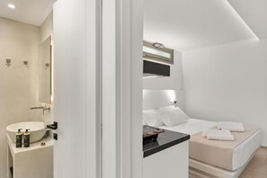 Ein modernes Badezimmer mit Waschbecken, Spiegel und Dusche, alles in Weiß.