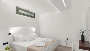 Quarto moderno com cama, mesa de cabeceira e uma pequena planta em cima de um criado-mudo.