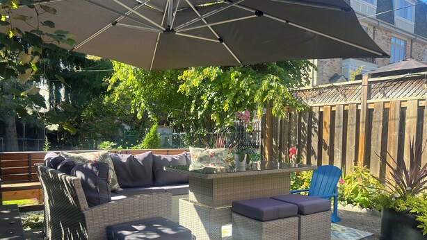 Eine Terrasse im Freien mit Korbmöbeln, einer Holzbank und einem blauen Stuhl.