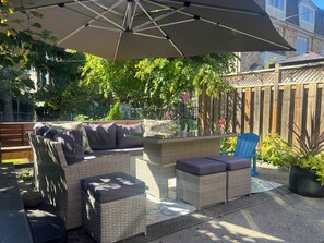 An outdoor patio with wicker furniture, a wooden bench, and a blue chair. - Gorgeous renovated 1 bedroom basement suite located in Toronto's  upper beaches. (Toronto)