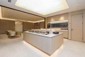 A modern kitchen with a central island, built-in appliances, and a dining area with chairs. - Ji Guangzhou Beijing Road Tuanyida Square (Guangzhou)