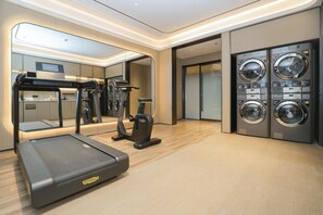 A modern gym with a treadmill, elliptical, and stationary bike, and a laundry area with two washing machines. - Ji Guangzhou Beijing Road Tuanyida Square (Guangzhou)