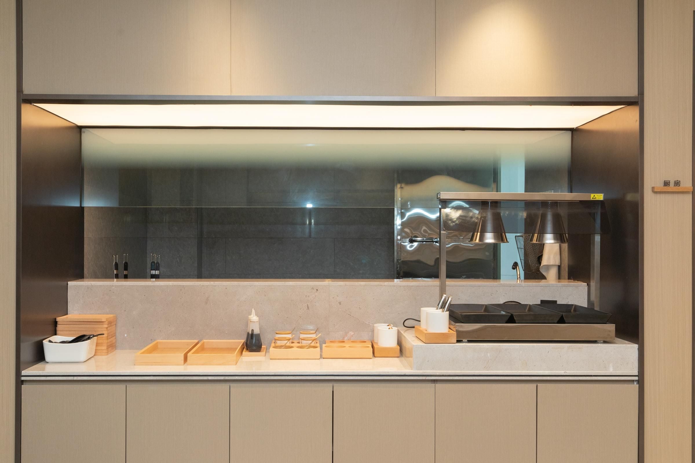 Une cuisine moderne dotée d’un évier en acier inoxydable, d’un four encastré et d’un grand miroir au-dessus du plan de travail.