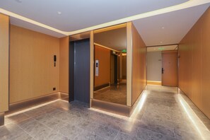 Un pasillo moderno de hotel con espejo, teléfono y ascensor.