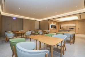 Een moderne hotelkamer met een keukenhoek, houten meubels en een plafond met inbouwspots.