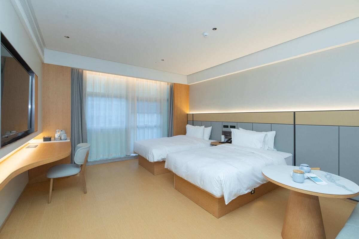 A modern hotel room with a large bed, a desk, and a TV.