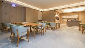 A modern dining area with wooden tables and chairs, a kitchen in the background, and a ceiling with recessed lighting. - Ji Guangzhou Beijing Road Tuanyida Square (Guangzhou)