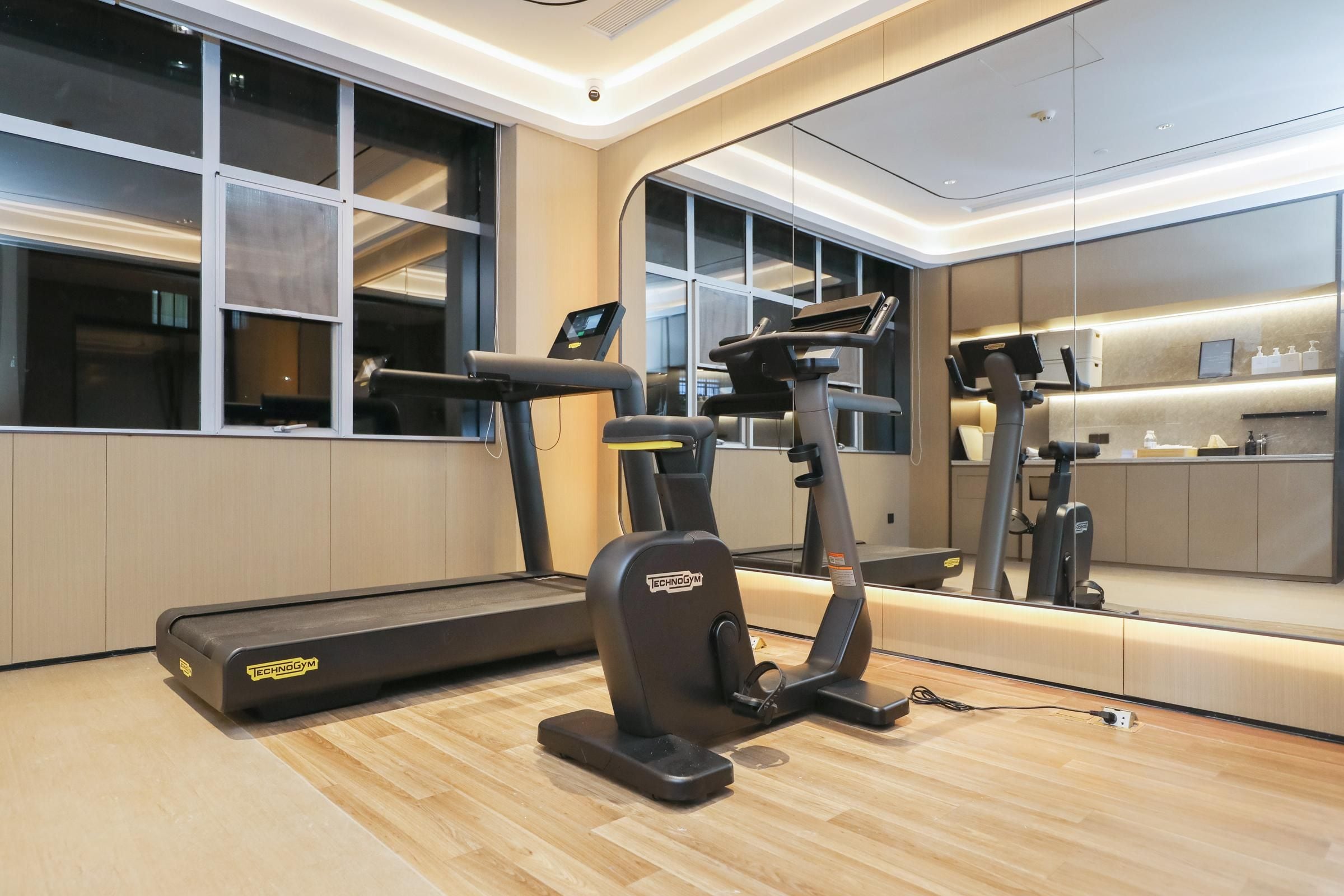 A modern gym with a treadmill, elliptical, and a stationary bike.