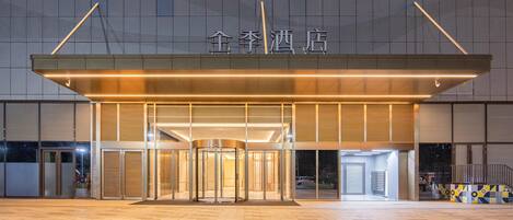A hotel entrance with a revolving door, a flat roof, and a sign above the entrance.