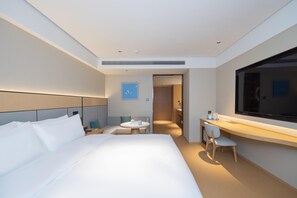 A modern hotel room with a large bed, a desk with a chair, a small table, and a TV. - Ji Guangzhou Nansha Phoenix Avenue Huanyu City (Guangzhou)