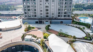 Un hotel moderno de gran altura, con un patio central que cuenta con una piscina, rodeado de zonas ajardinadas y un paseo cubierto.