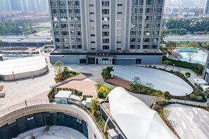 A high-rise hotel with a modern design, featuring a central courtyard with a swimming pool, surrounded by landscaped areas and a covered walkway.
