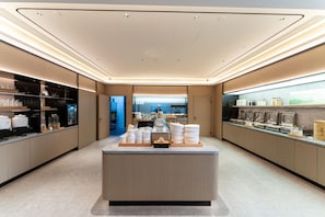 Un área de cocina moderna y bien iluminada con una isla central, estantes con utensilios de cocina y vistas al comedor.