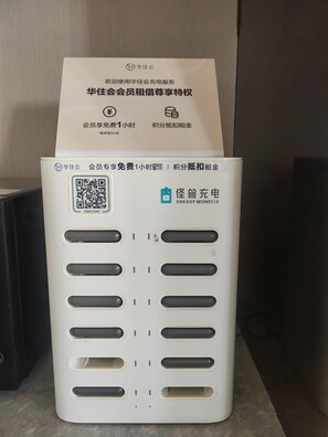 Un cuadro eléctrico blanco con un código QR y una etiqueta que indica un servicio gratuito de una hora para miembros del Huajiu Club.