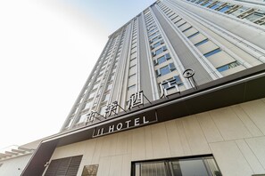Un edificio de hotel alto con una fachada moderna y un letrero que dice "JI HOTEL".
