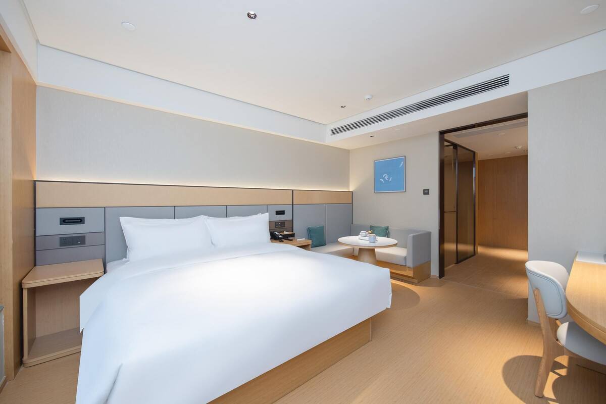 Una camera d'albergo moderna con un letto grande, comodini, una scrivania e un'area salotto.