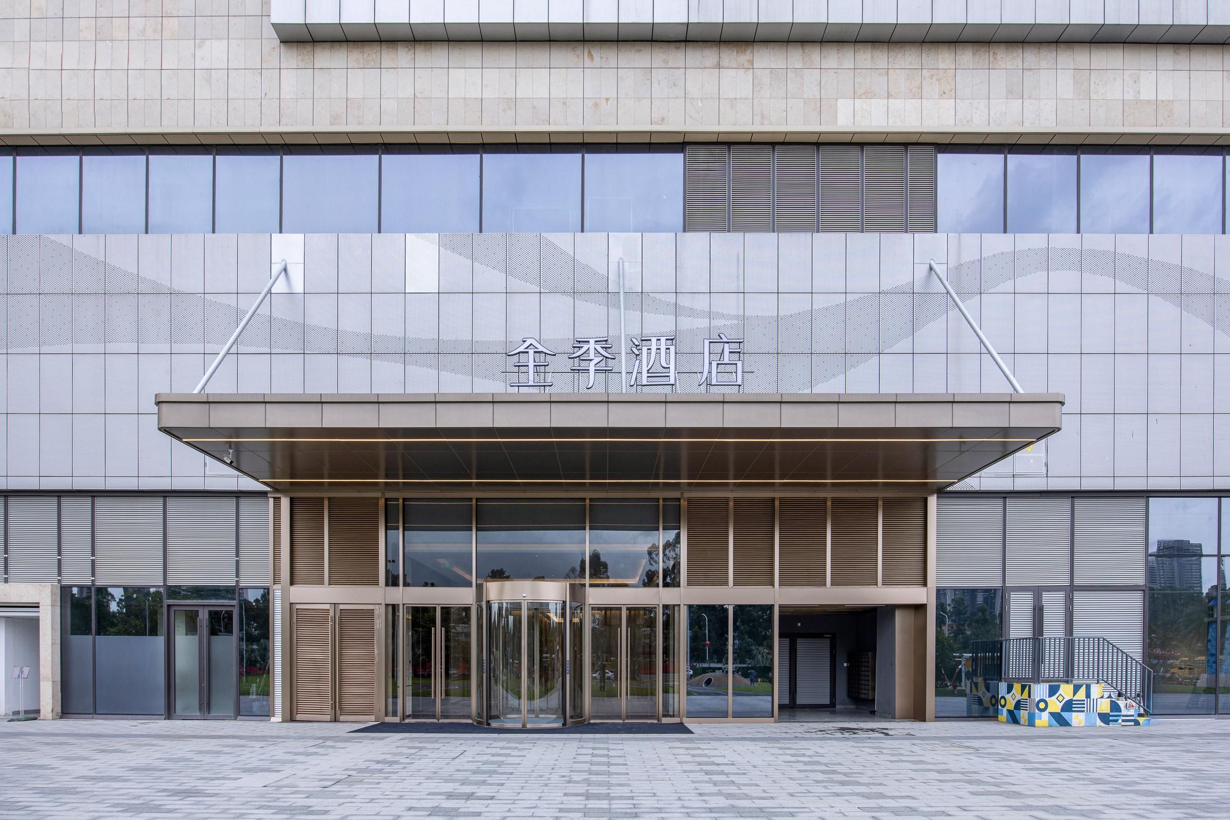 A modern building with a large entrance, glass doors, and a sign above the doors.
