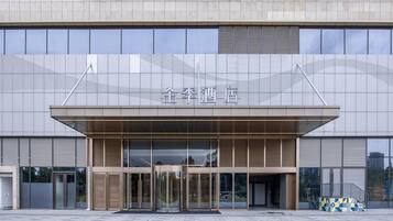 A modern building with a large entrance, glass doors, and a sign above the doors.