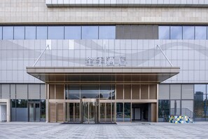 Un edificio moderno con una entrada amplia, puertas de vidrio y un cartel sobre las puertas.