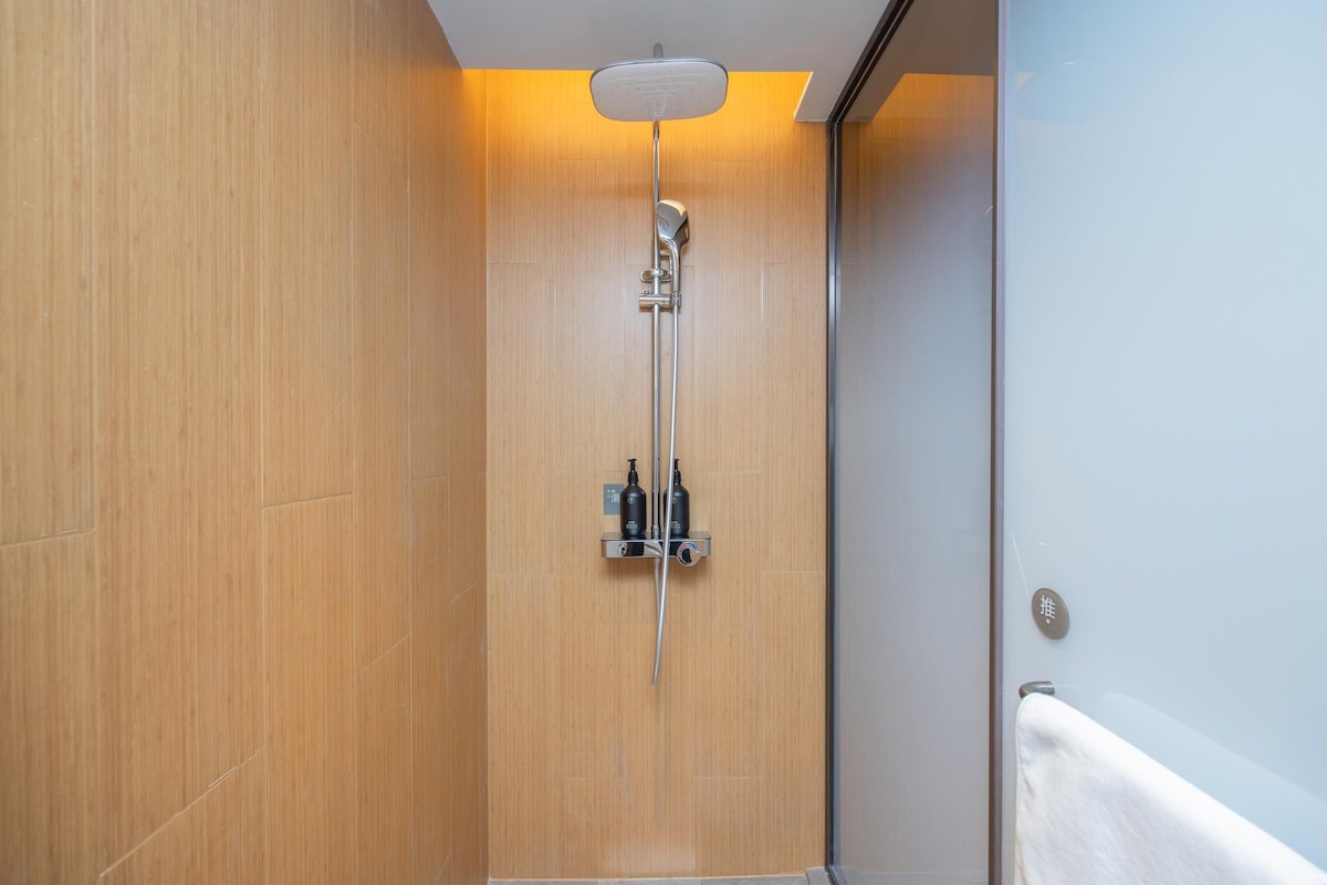Una ducha moderna con cabezal de ducha manual y panel de control en la pared.