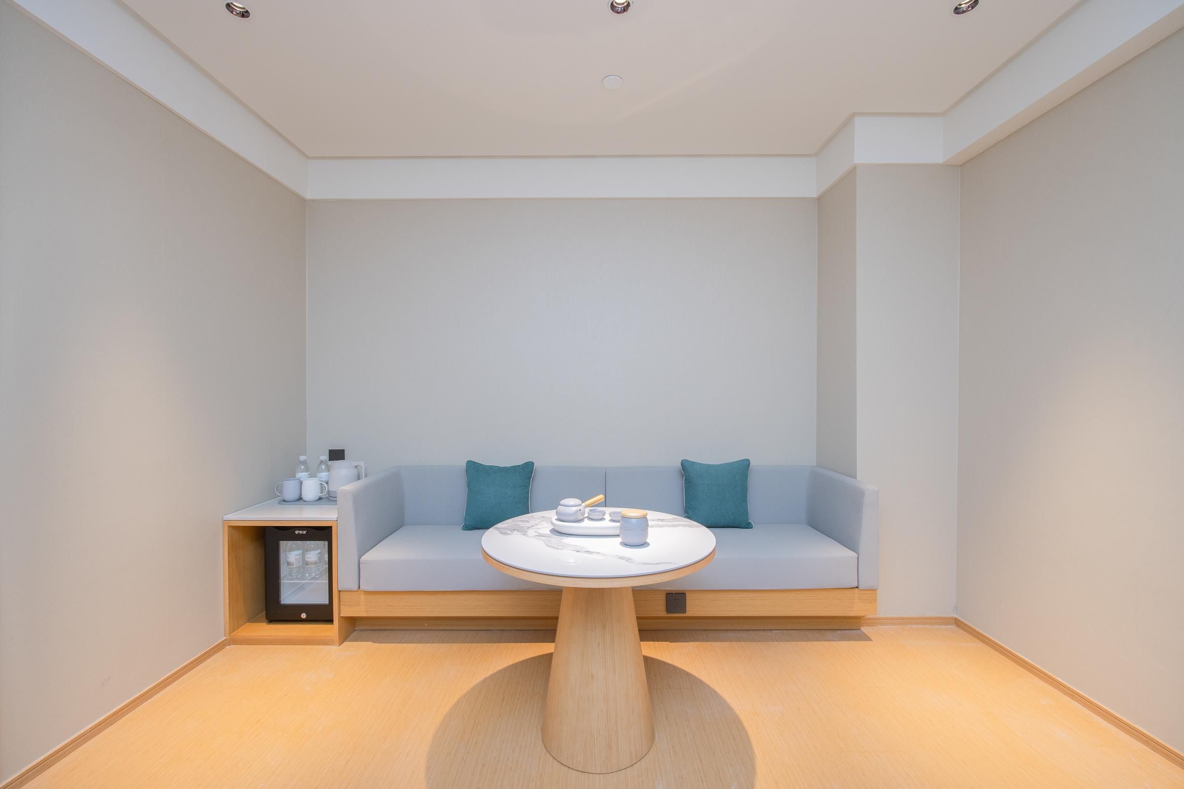 A modern room with a round table, a sofa, and a small side table with a device.