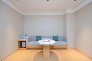 Una habitación moderna con una mesa redonda, un sofá y una pequeña mesita auxiliar con un dispositivo.