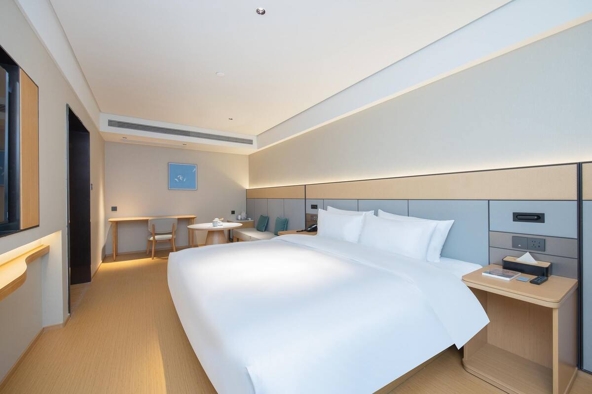 Una camera d'albergo moderna con un letto grande, un comodino e una scrivania con una sedia.