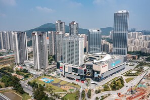 A high-rise building complex with multiple residential and commercial structures, surrounded by greenery and a clear sky.