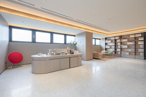Una biblioteca moderna con un mostrador central, estanterías y zonas de descanso.