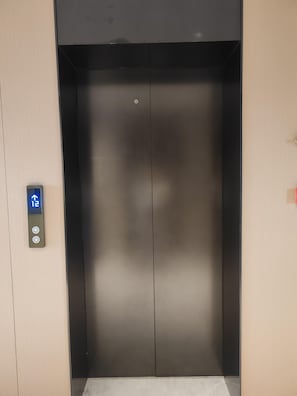 Un ascensor con una pantalla digital que muestra el piso número 12 y botones para subir y bajar.